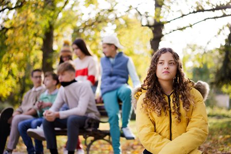 Girl on bench with teenagers behind her